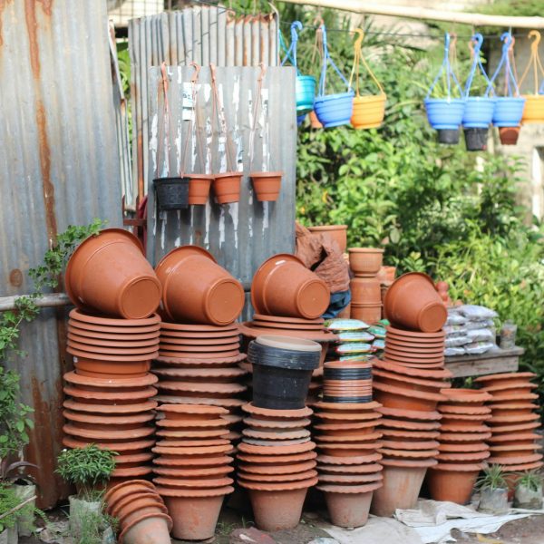 A variety of stacked and hanging garden pots outdoors, showcasing vibrant colors and textures.